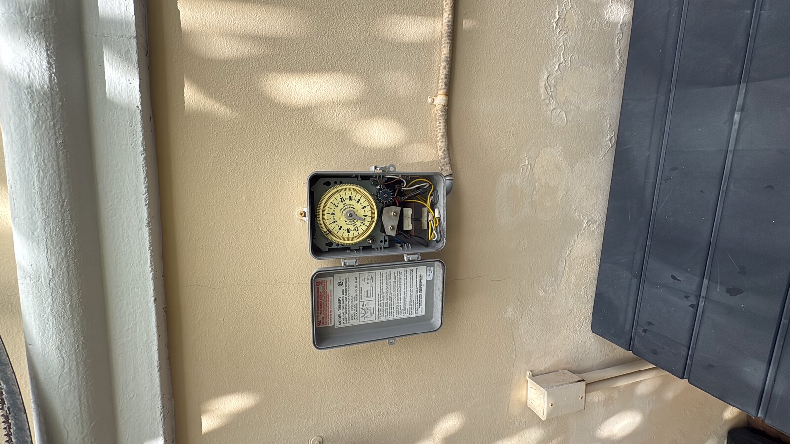 old mechanical sprinkler timer with surge-damaged board in a Miami garage